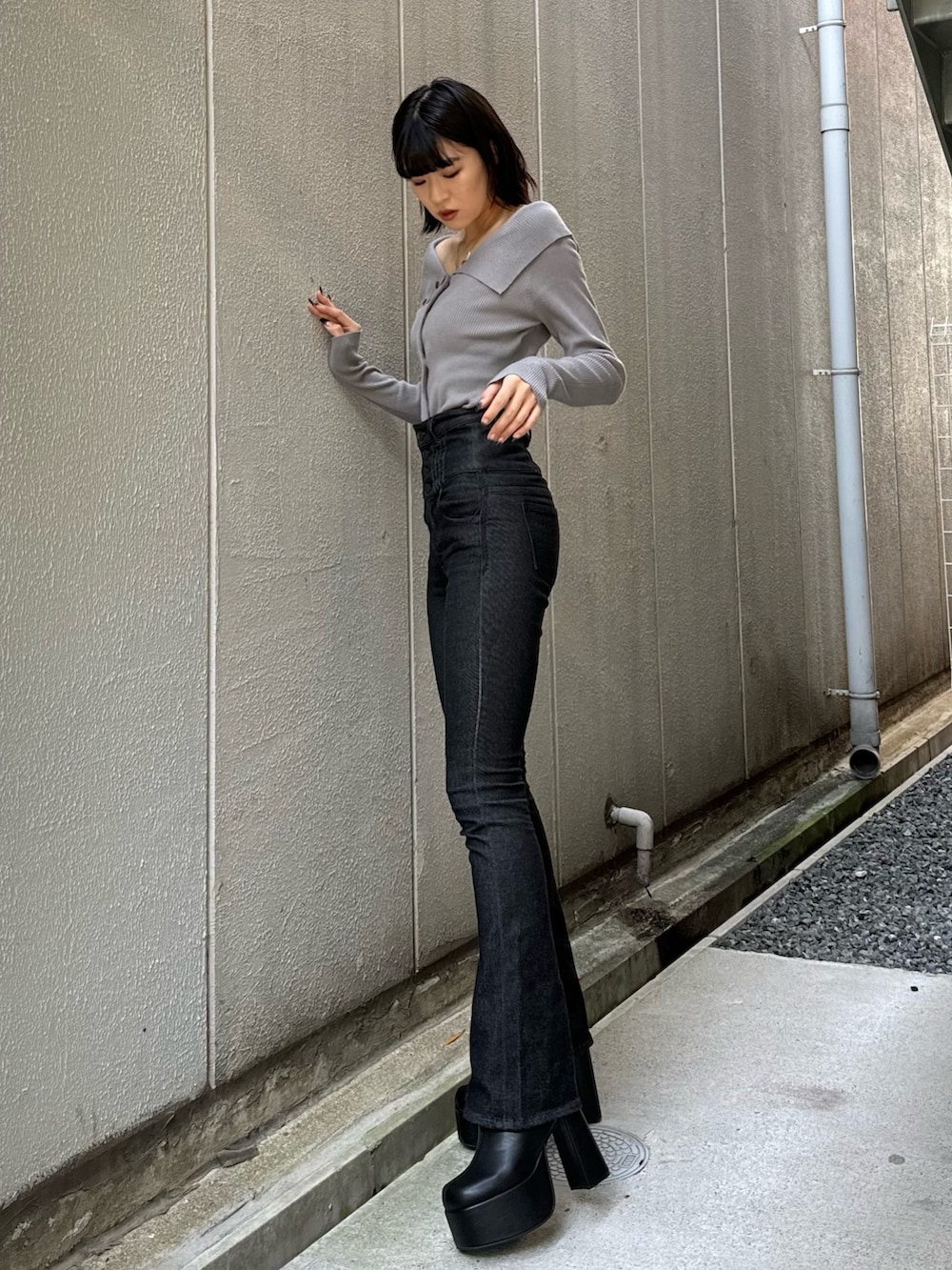 ブラック系のデニムパンツ、ブラック系のブーツ、グレー系のニット/セーターを着用したレディースの秋コーディネートの4枚目の写真