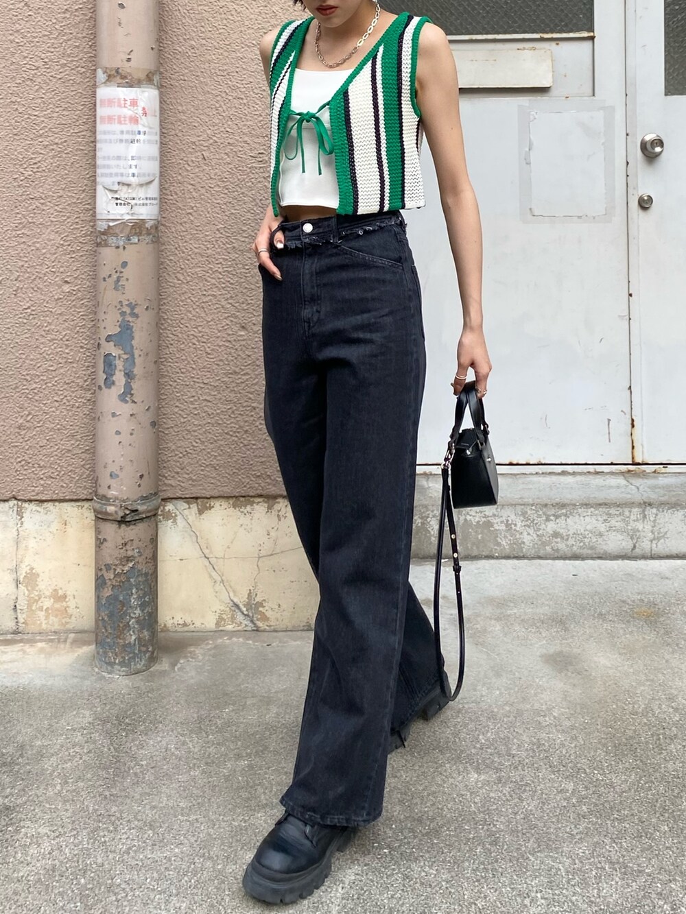 ブラック系のデニムパンツ、ブラック系のブーツ、ブラック系のハンドバッグを着用したレディースの春コーディネートの2枚目の写真