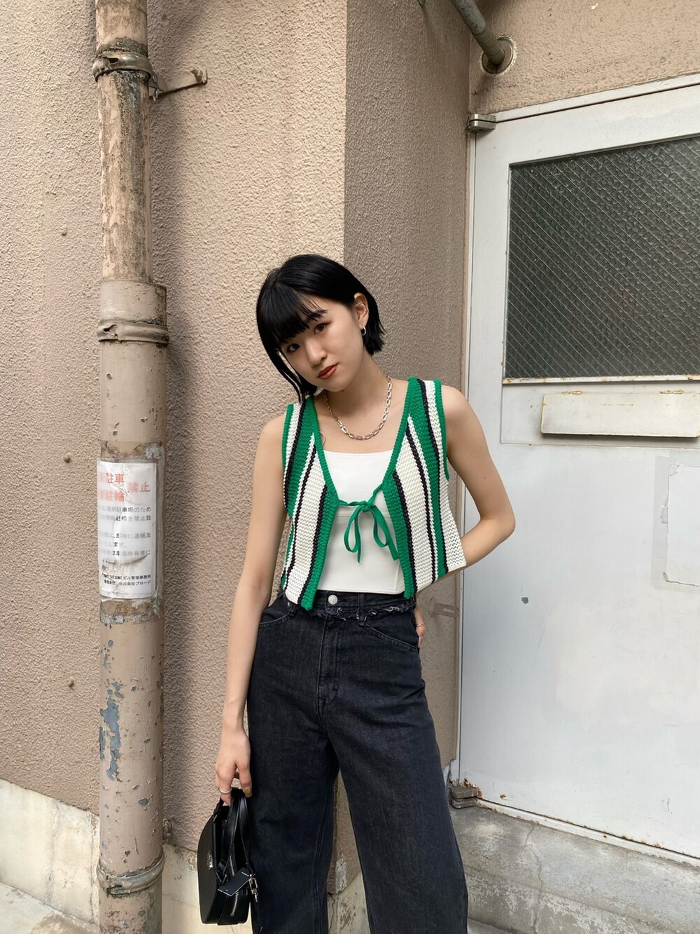 ブラック系のデニムパンツ、ブラック系のブーツ、ブラック系のハンドバッグを着用したレディースの春コーディネートの5枚目の写真