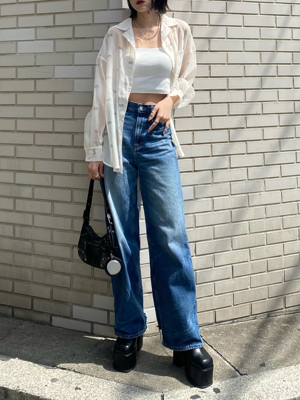 ブラック系のサンダル、ブラック系のハンドバッグ、ブルー系のデニムパンツを着用したレディースの春コーディネートの3枚目の写真