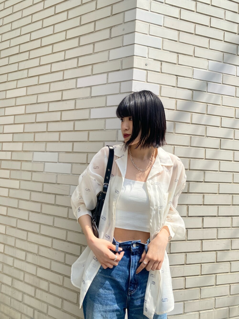 ブラック系のサンダル、ブラック系のハンドバッグ、ブルー系のデニムパンツを着用したレディースの春コーディネートの7枚目の写真