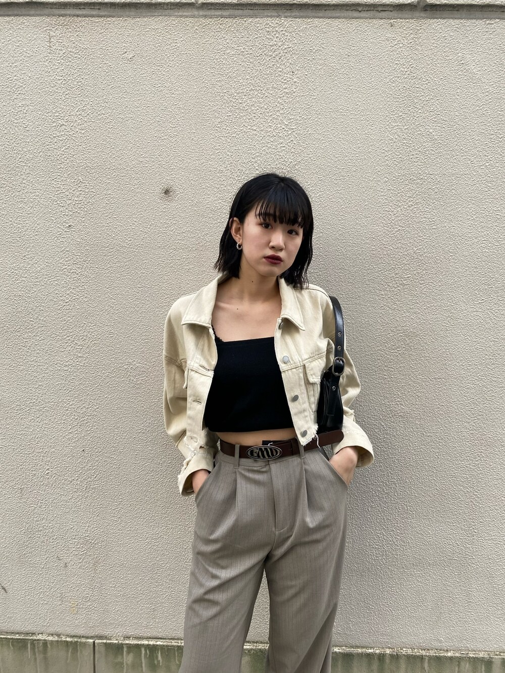 ホワイト系のデニムジャケット、ブラック系のキャミソール、ブラック系のハンドバッグを着用したレディースの春コーディネートの6枚目の写真