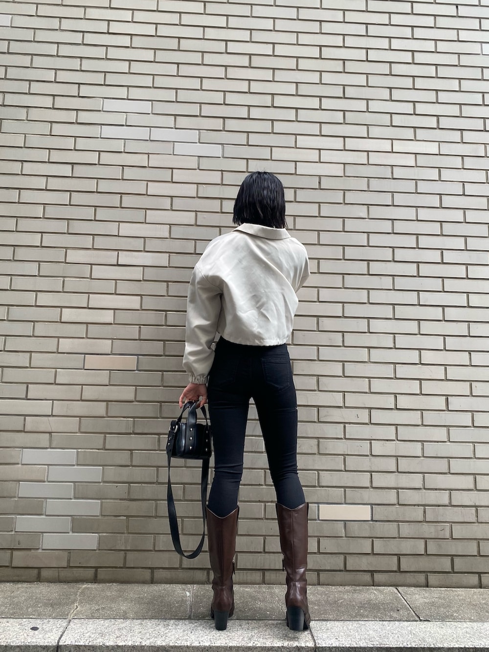 ブラック系のブーツ、ブラック系のデニムパンツ、ホワイト系のブルゾンを着用したレディースの冬コーディネートの5枚目の写真
