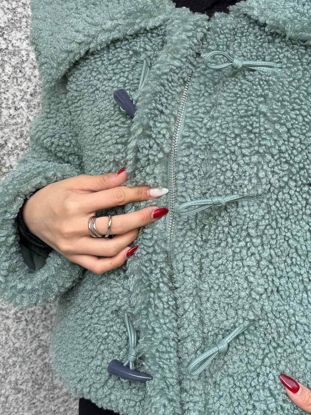 グリーン系のブルゾン、ブラック系のスカート、その他のブーツを着用したレディースの冬コーディネートの9枚目の写真