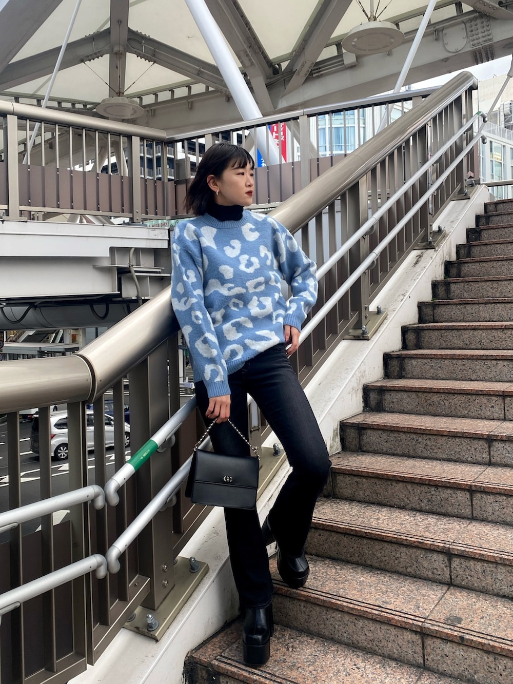 ブルー系のニット/セーター、ブラック系のハンドバッグ、ブラック系のブーツを着用したレディースの冬コーディネートの2枚目の写真