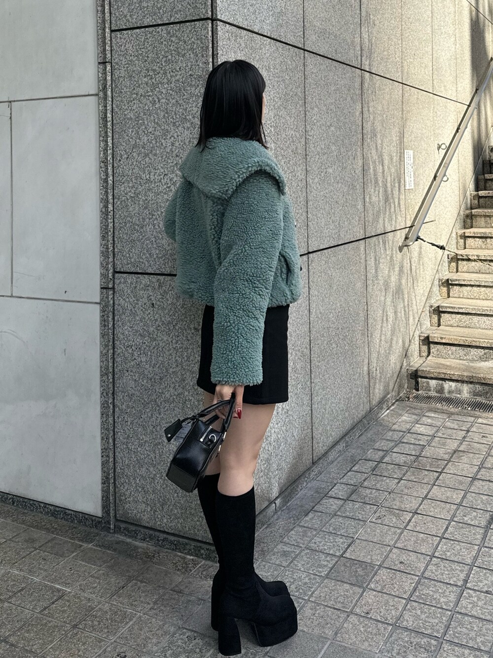 グリーン系のブルゾン、ブラック系のスカート、その他のブーツを着用したレディースの冬コーディネートの3枚目の写真