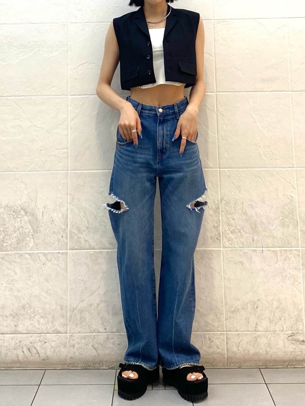 ブラック系のサンダル、ブルー系のデニムパンツ、ホワイト系のニット/セーターを着用したレディースの夏コーディネートの2枚目の写真