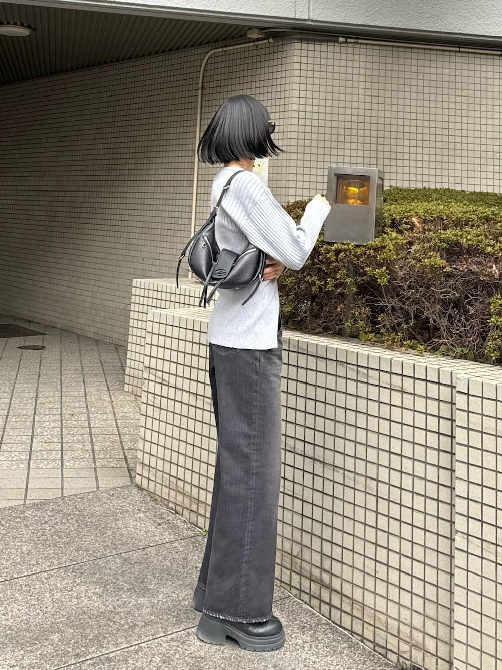 ブラック系のブーツ、ブラック系のデニムパンツ、グレー系のニット/セーターを着用したレディースの冬コーディネートの2枚目の写真