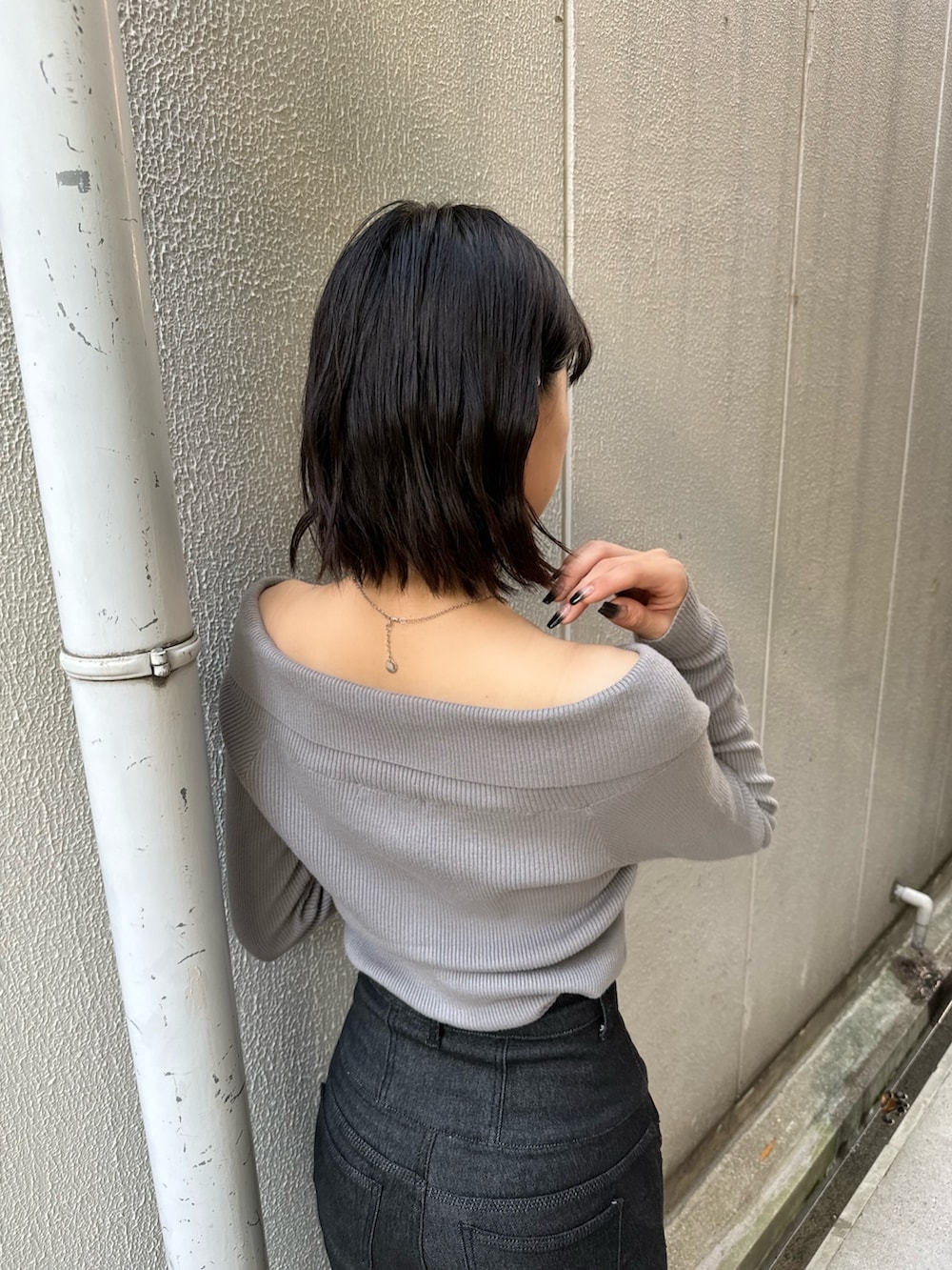 ブラック系のデニムパンツ、ブラック系のブーツ、グレー系のニット/セーターを着用したレディースの秋コーディネートの9枚目の写真