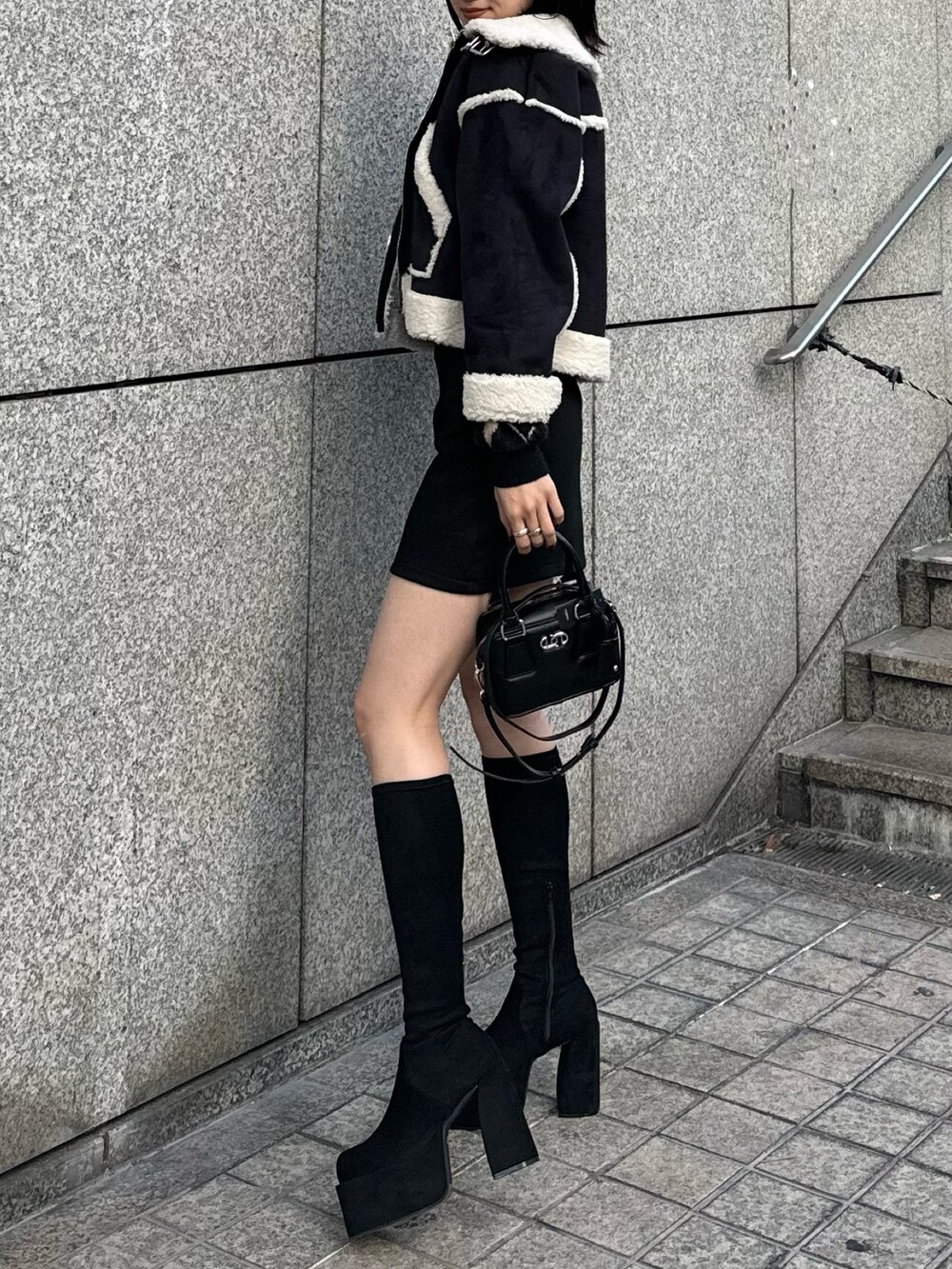 その他のブーツ、ブラック系のスカート、ブラック系のハンドバッグを着用したレディースの冬コーディネートの2枚目の写真