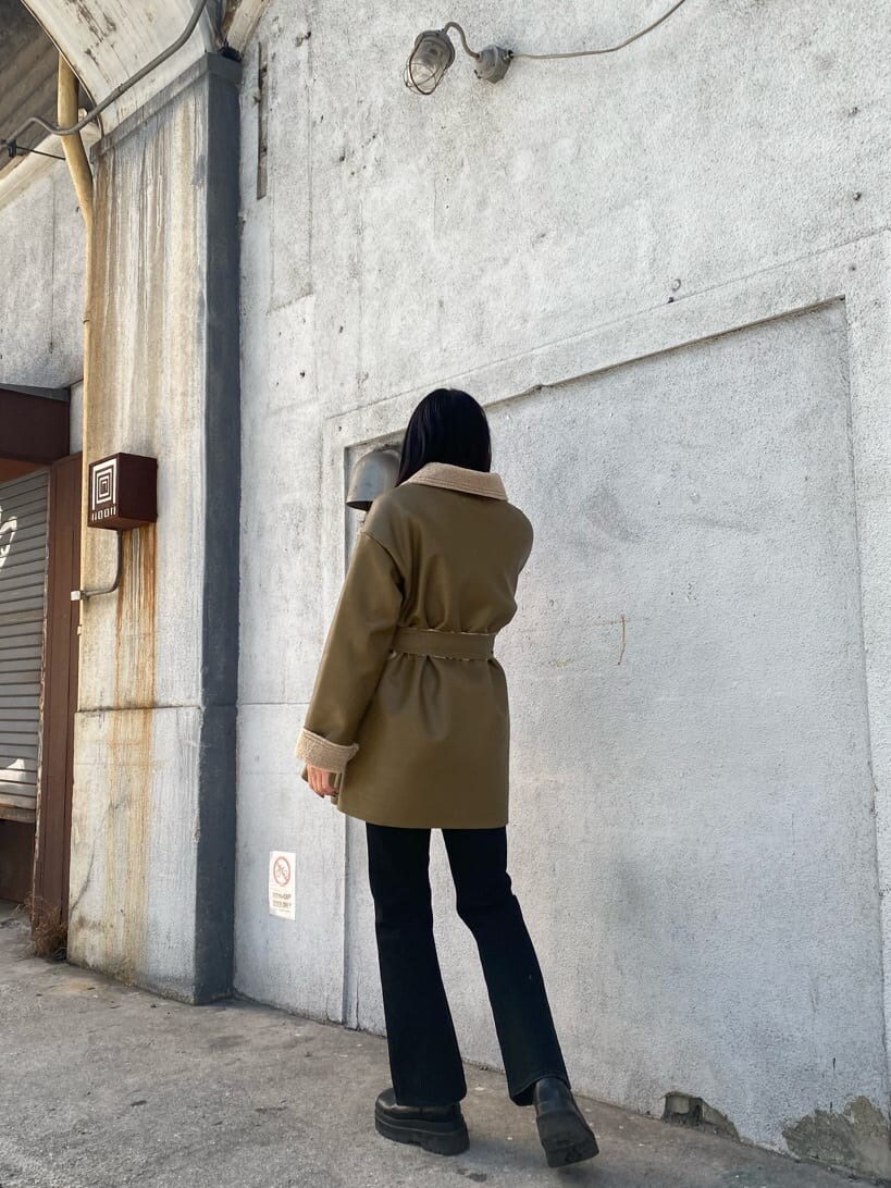 ホワイト系のニット/セーター、ホワイト系のハンドバッグ、ベージュ系のムートンコートを着用したレディースの冬コーディネートの3枚目の写真