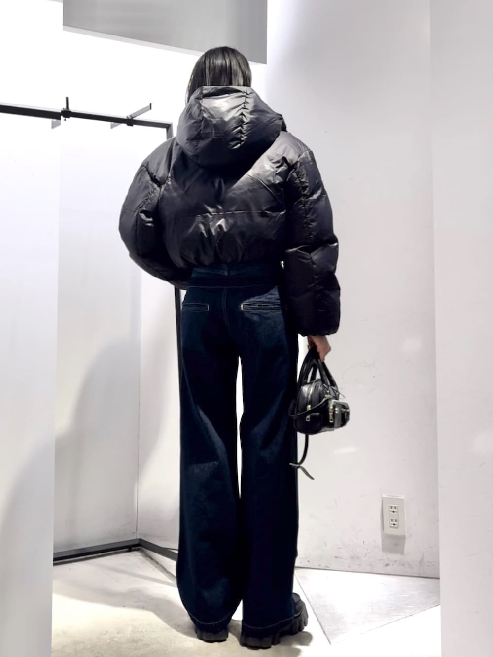 ブルー系のデニムパンツ、ブラック系のハンドバッグ、ブラック系のダウンジャケット/コートを着用したレディースの冬コーディネートの3枚目の写真