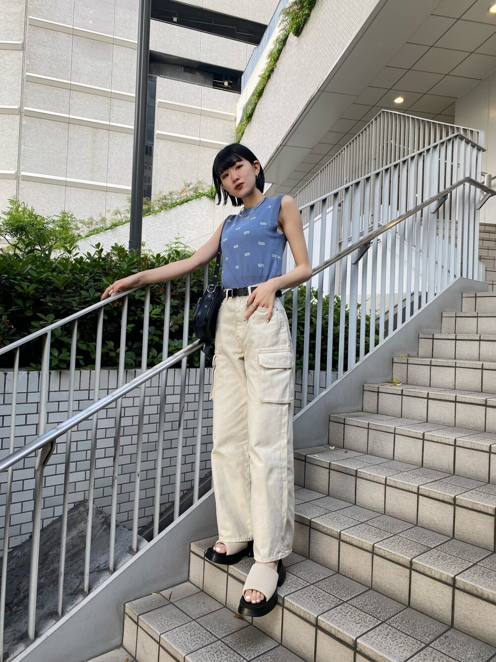 ブラック系のショルダーバッグ、ホワイト系のサンダル、ホワイト系のデニムパンツを着用したレディースの春コーディネートの3枚目の写真