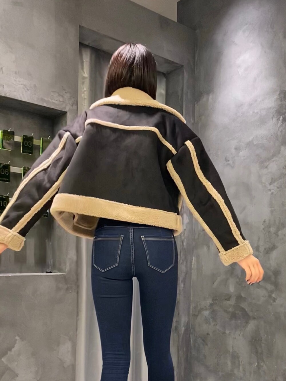 ブルー系のデニムパンツ、ブラック系のブーツ、ブラック系のムートンコートを着用したレディースの秋コーディネートの3枚目の写真