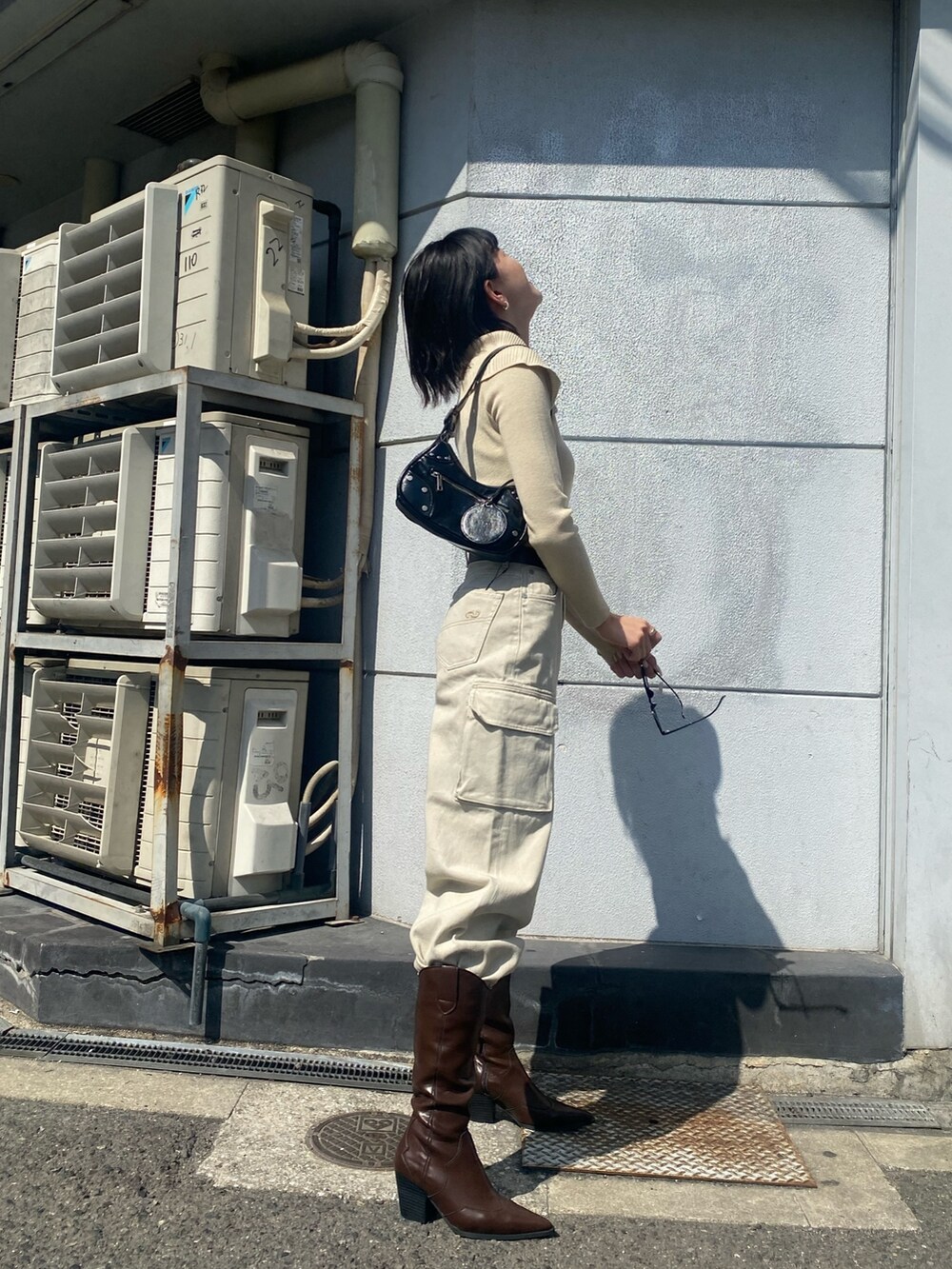 ブラウン系のブーツ、ホワイト系のデニムパンツ、ブラック系のハンドバッグを着用したレディースの春コーディネートの4枚目の写真