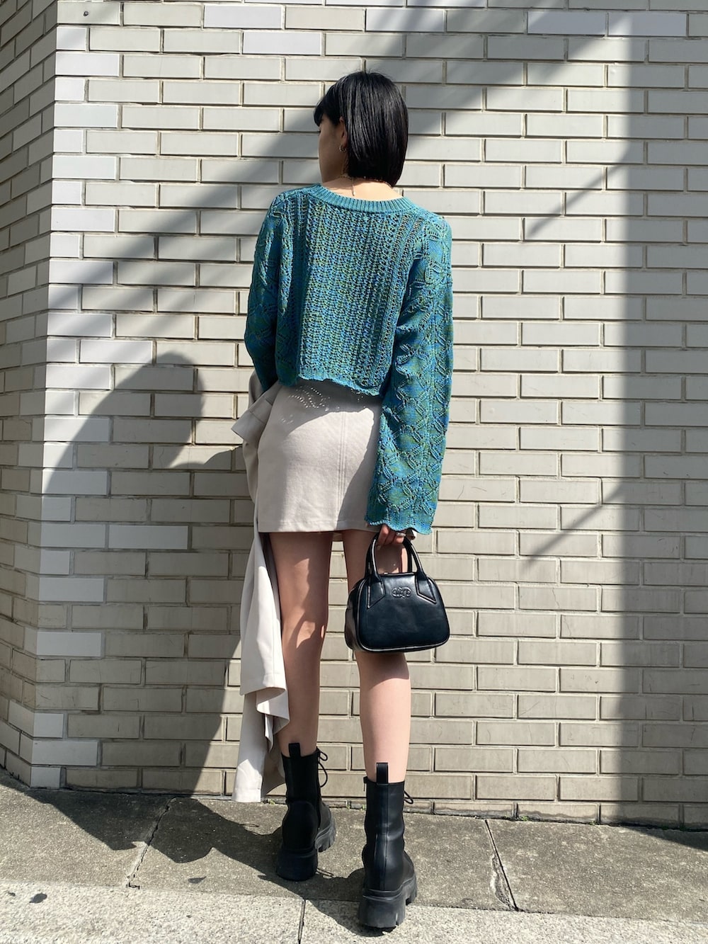ホワイト系のスカート、ブルー系のニット/セーター、ホワイト系のトレンチコートを着用したレディースの春コーディネートの2枚目の写真