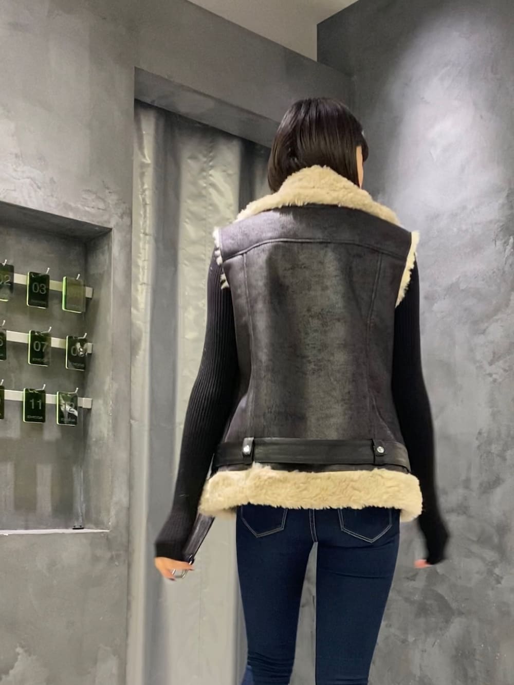 ブルー系のデニムパンツ、ブラック系のブーツ、ブラック系のベストを着用したレディースの秋コーディネートの2枚目の写真