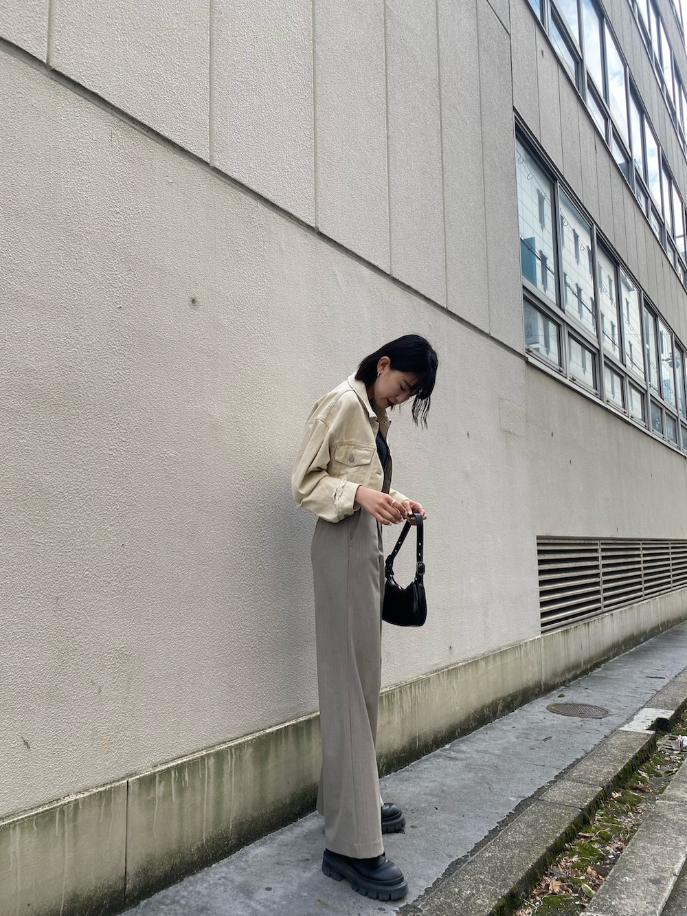 ホワイト系のデニムジャケット、ブラック系のキャミソール、ブラック系のハンドバッグを着用したレディースの春コーディネートの5枚目の写真