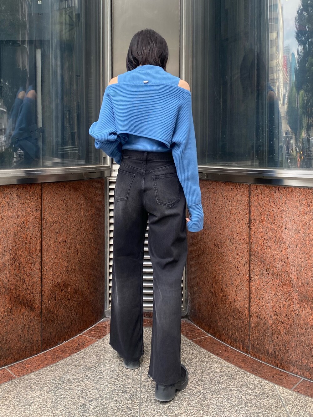 ブラック系のブーツ、ブラック系のデニムパンツ、ブルー系のニット/セーターを着用したレディースの秋コーディネートの2枚目の写真