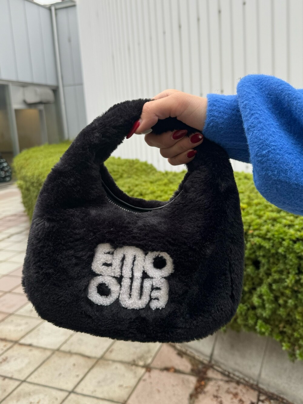 ブルー系のニット/セーター、ブラック系のデニムパンツ、ブラック系のハンドバッグを着用したレディースの冬コーディネートの7枚目の写真