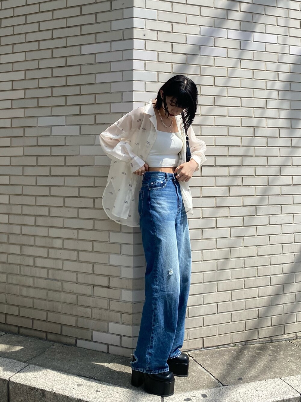 ブラック系のサンダル、ブラック系のハンドバッグ、ブルー系のデニムパンツを着用したレディースの春コーディネートの2枚目の写真