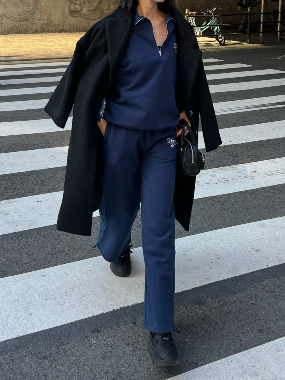 ブルー系のTシャツ/カットソー、ブルー系のTシャツ/カットソー、ブラック系のチェスターコートを着用したレディースの秋コーディネートの2枚目の写真