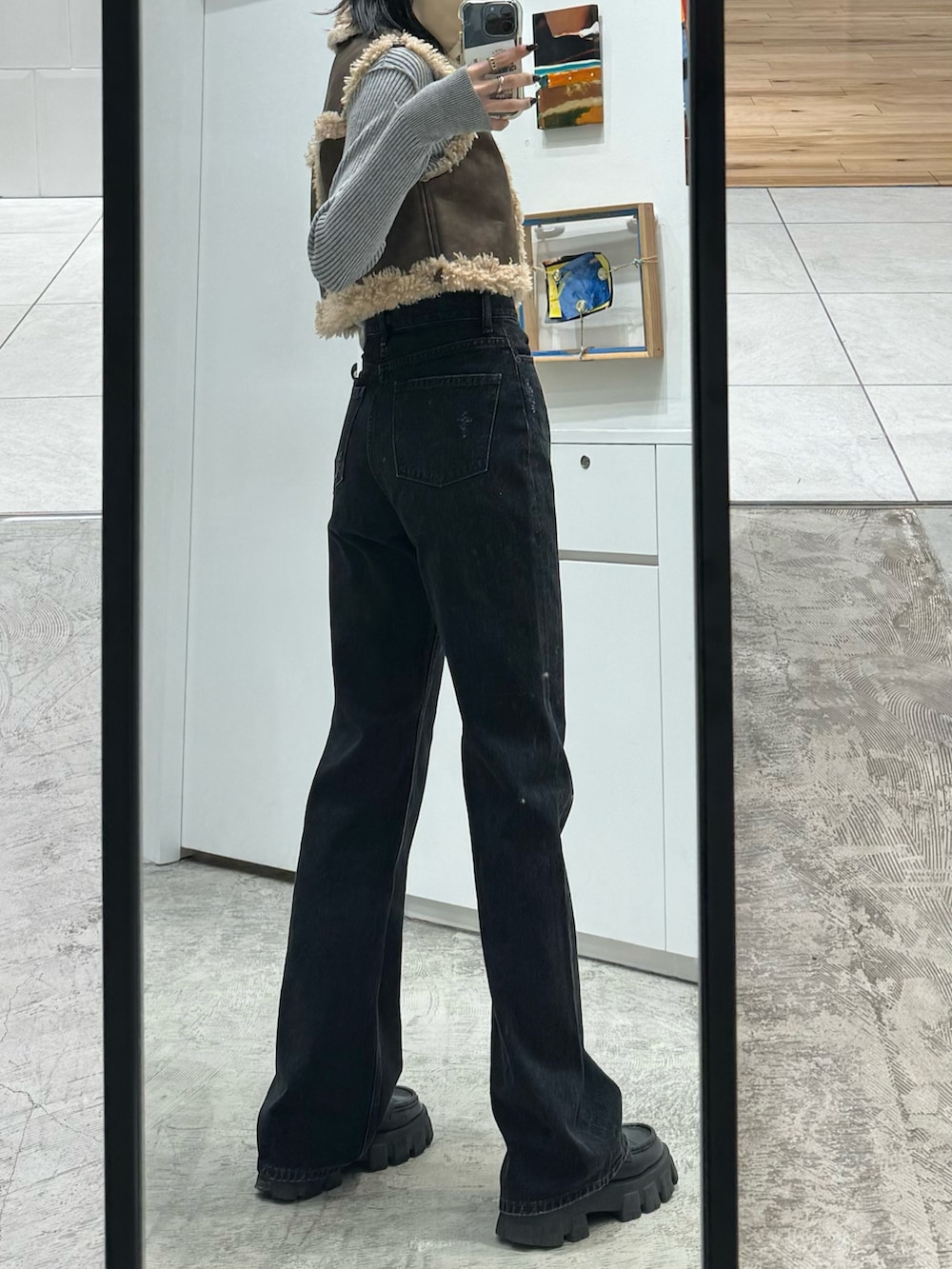 ブラック系のデニムパンツ、ブラウン系のベスト、グレー系のニット/セーターを着用したレディースの秋コーディネートの3枚目の写真