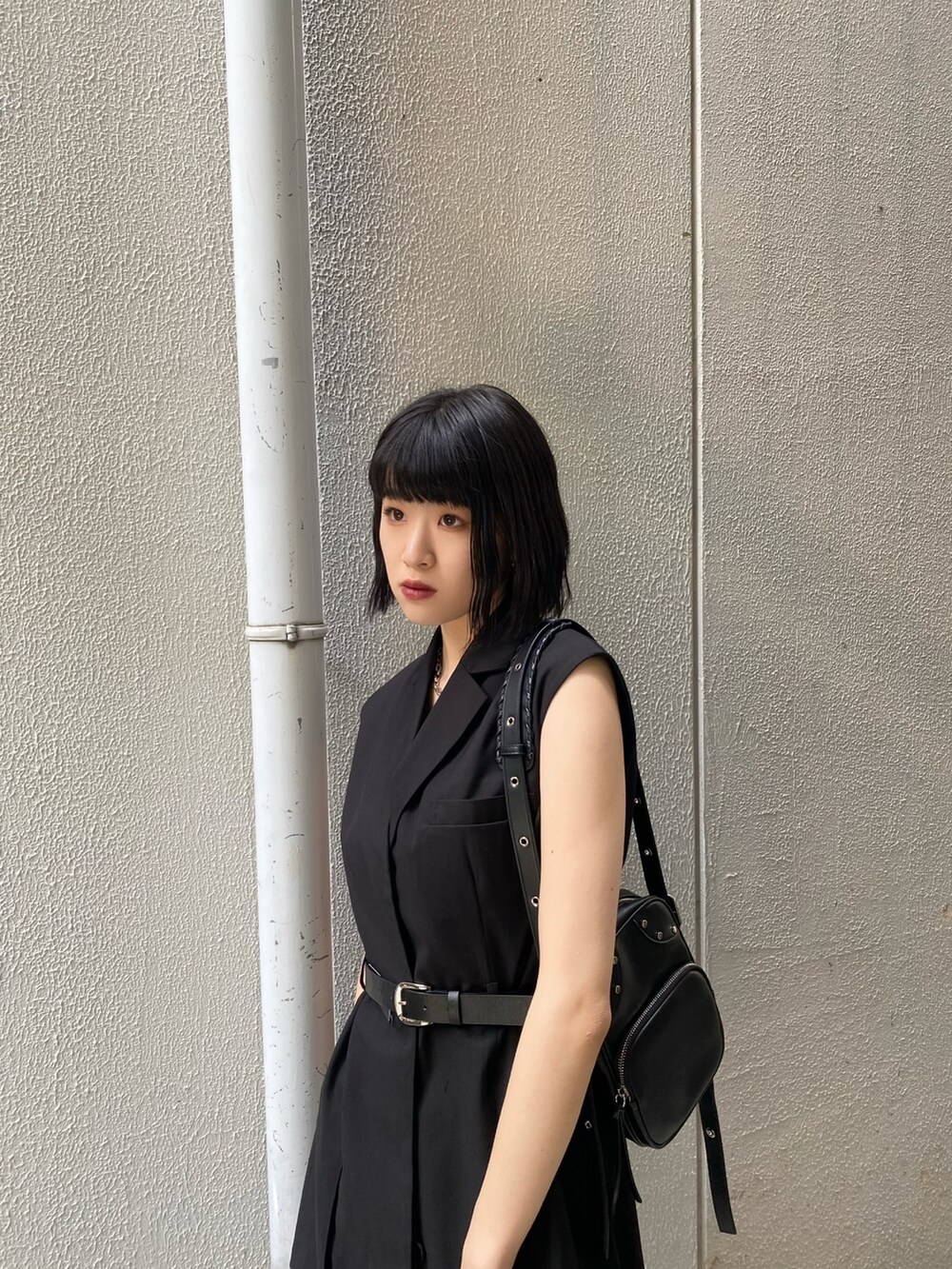 ブラック系のワンピース、ブラック系のサンダル、ブルー系のデニムパンツを着用したレディースの夏コーディネートの6枚目の写真