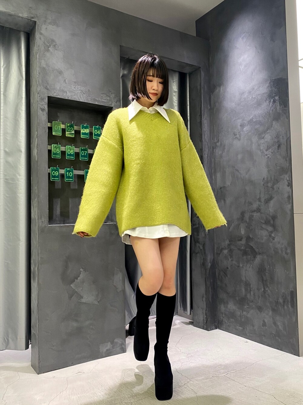 ブラック系のブーツ、イエロー系のニット/セーター、ホワイト系のワンピースを着用したレディースの冬コーディネートの8枚目の写真