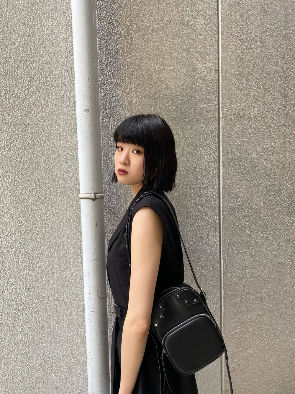 ブラック系のワンピース、ブラック系のサンダル、ブルー系のデニムパンツを着用したレディースの夏コーディネートの5枚目の写真