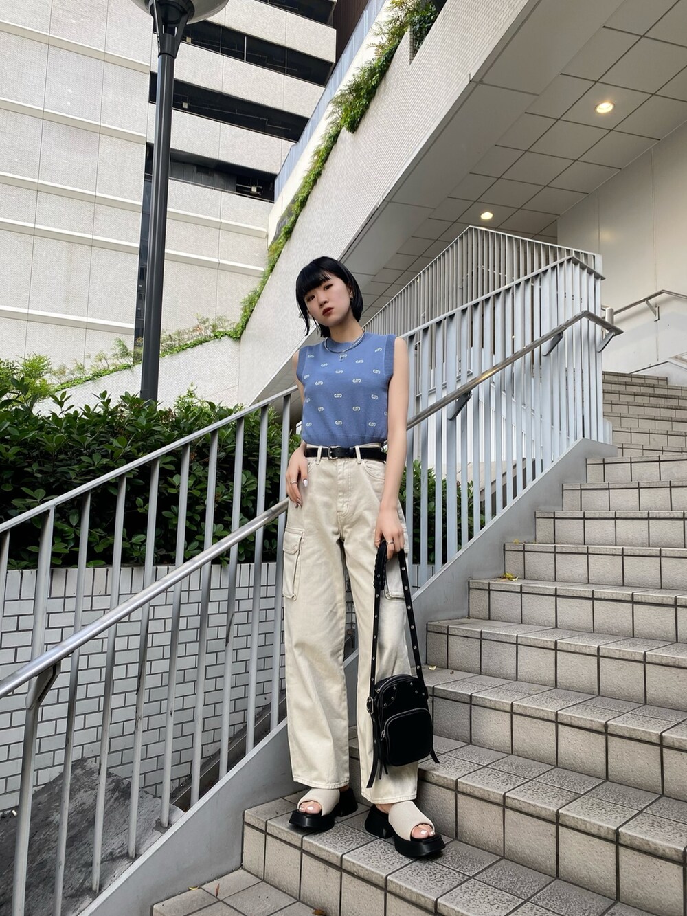 ブラック系のショルダーバッグ、ホワイト系のサンダル、ホワイト系のデニムパンツを着用したレディースの春コーディネートの2枚目の写真