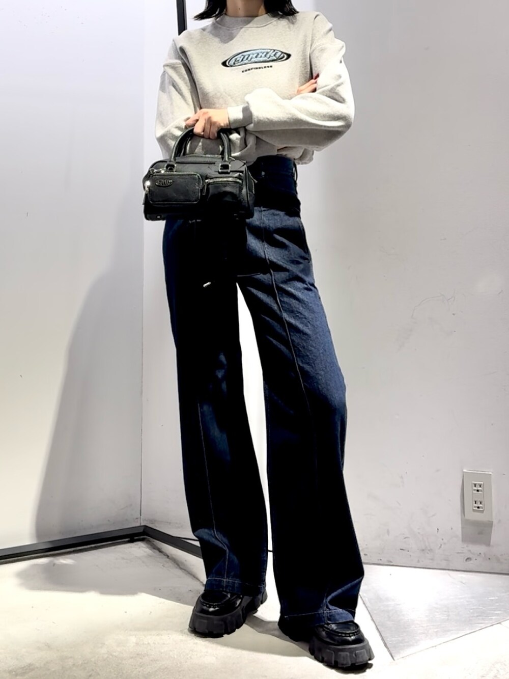 ブルー系のデニムパンツ、ブラック系のハンドバッグ、ブラック系のダウンジャケット/コートを着用したレディースの冬コーディネートの4枚目の写真