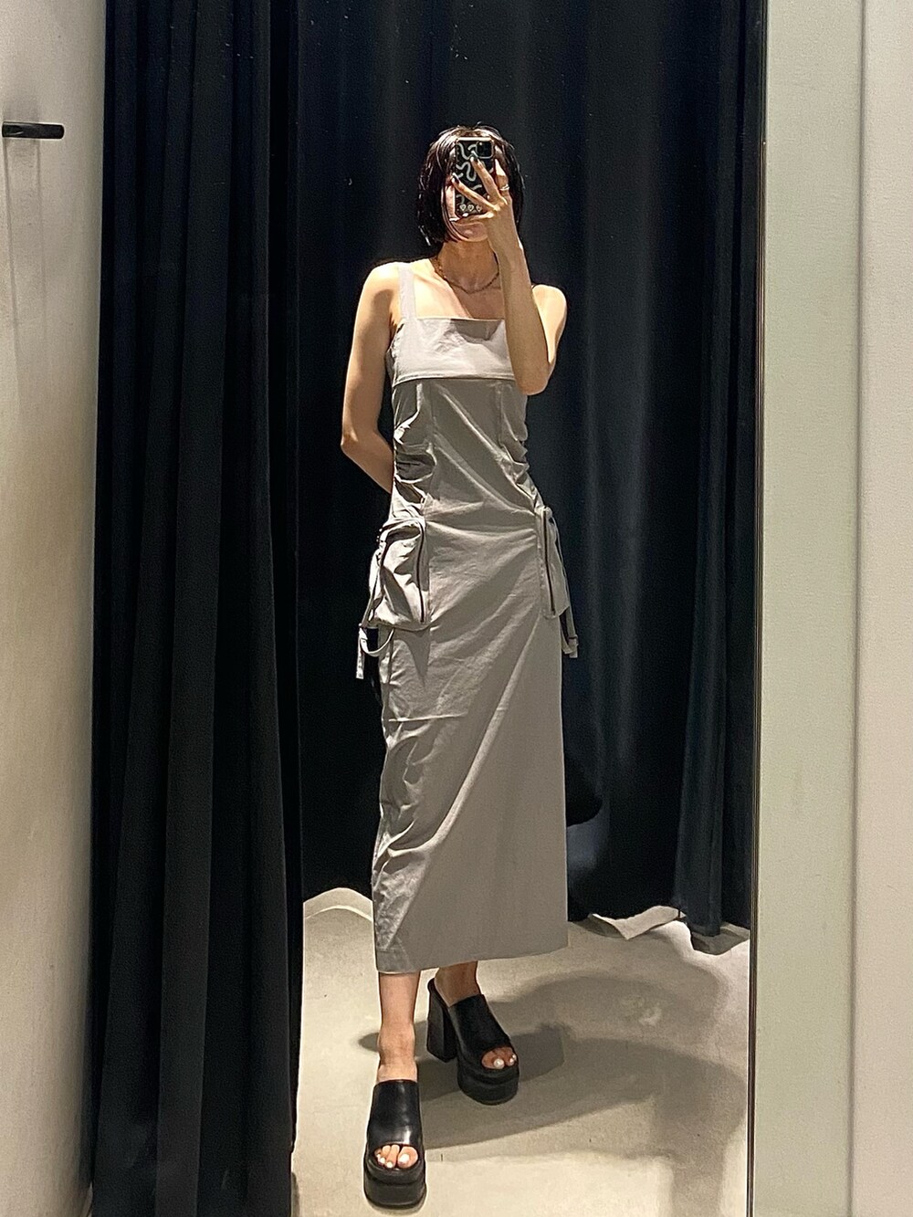 グレー系のワンピース、ブラック系のサンダル、ホワイト系のキャミソールを着用したレディースの夏コーディネートの2枚目の写真