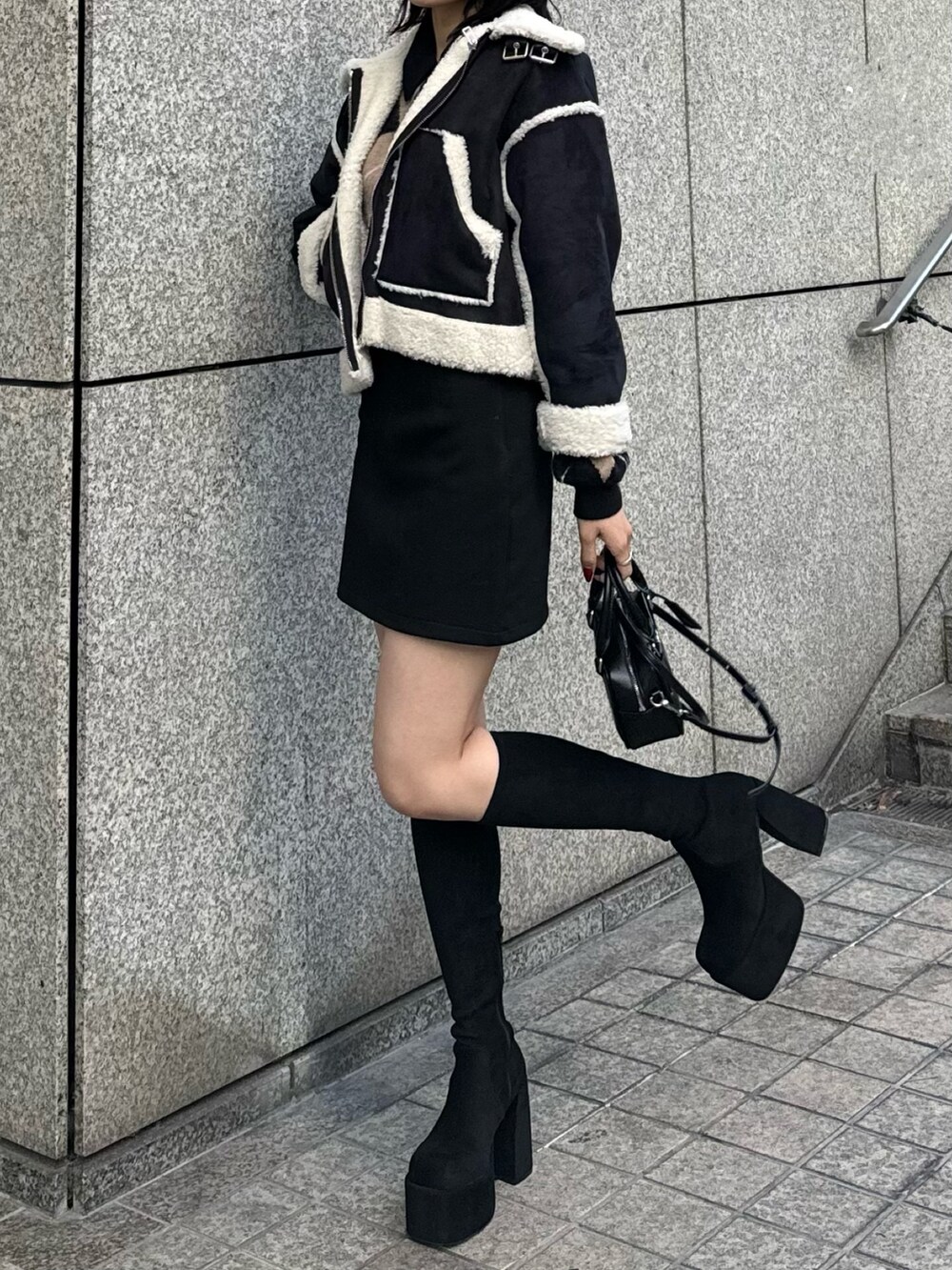 その他のブーツ、ブラック系のスカート、ブラック系のハンドバッグを着用したレディースの冬コーディネートの4枚目の写真