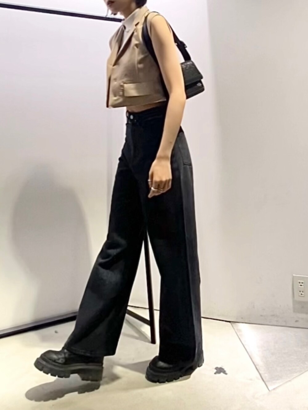 ブラック系のデニムパンツ、ブラック系のブーツ、ブラック系のショルダーバッグを着用したレディースの夏コーディネートの4枚目の写真