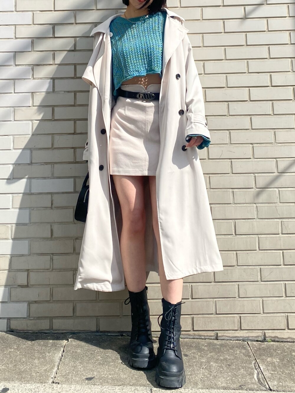 ホワイト系のスカート、ブルー系のニット/セーター、ホワイト系のトレンチコートを着用したレディースの春コーディネートの4枚目の写真