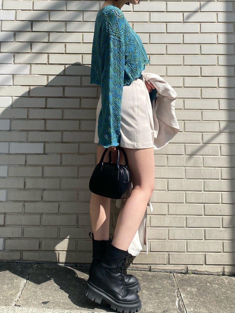 ホワイト系のスカート、ブルー系のニット/セーター、ホワイト系のトレンチコートを着用したレディースの春コーディネートの3枚目の写真