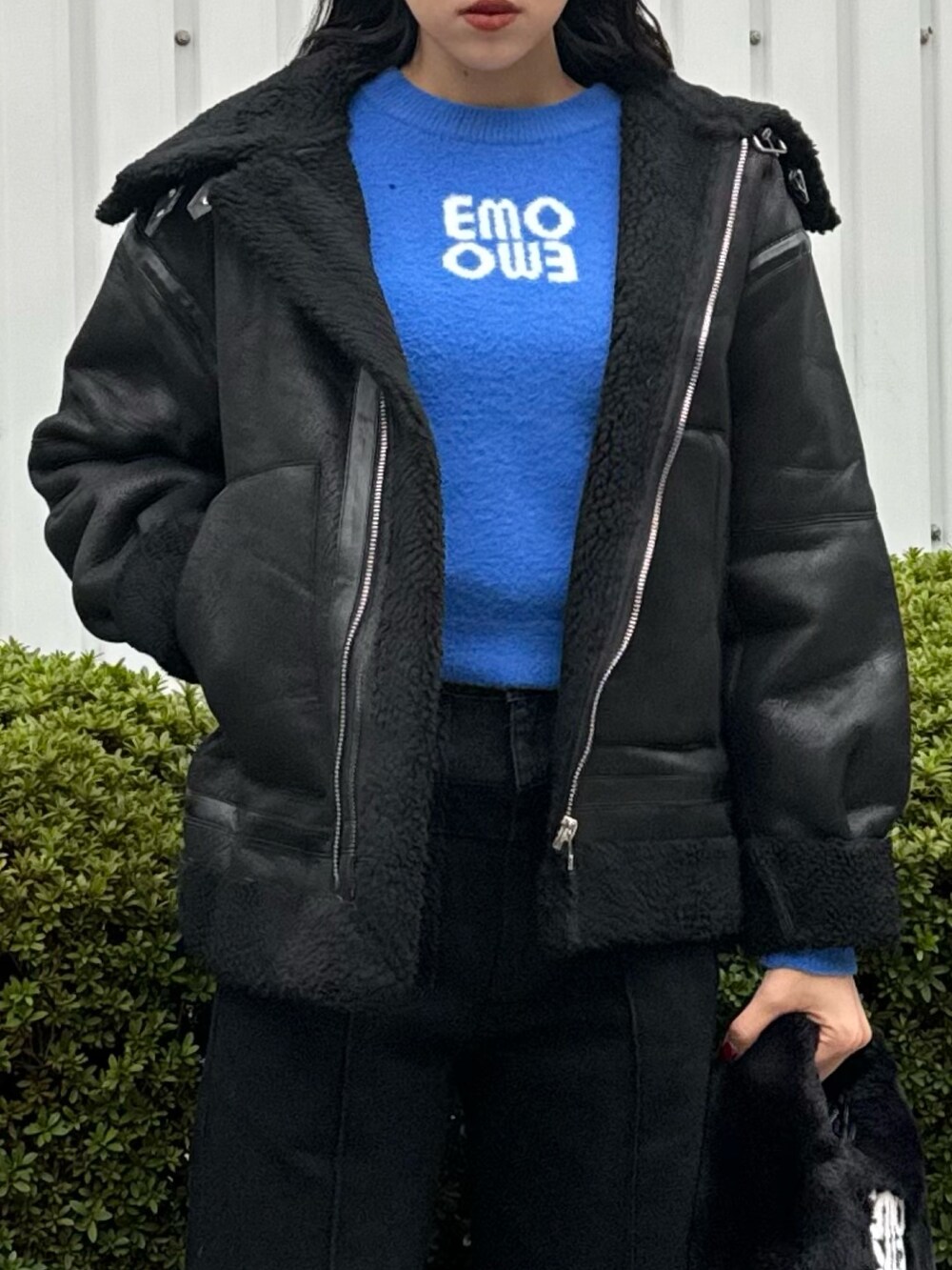 ブラック系のデニムパンツ、ブラック系のハンドバッグ、ブラック系のムートンコートを着用したレディースの冬コーディネートの6枚目の写真