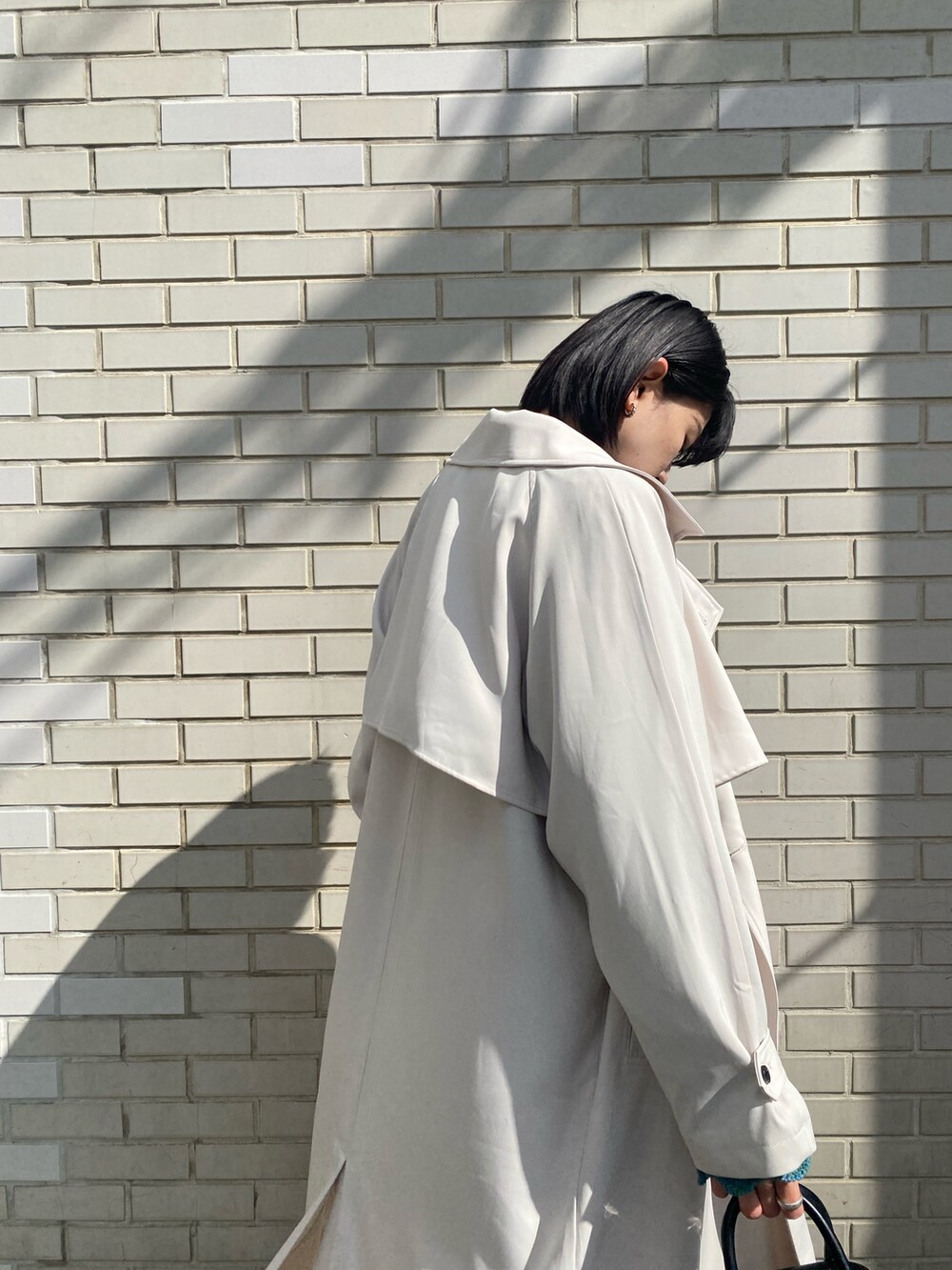 ホワイト系のスカート、ブルー系のニット/セーター、ホワイト系のトレンチコートを着用したレディースの春コーディネートの7枚目の写真