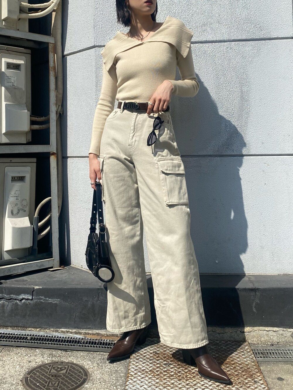 ブラウン系のブーツ、ホワイト系のデニムパンツ、ブラック系のハンドバッグを着用したレディースの春コーディネートの5枚目の写真