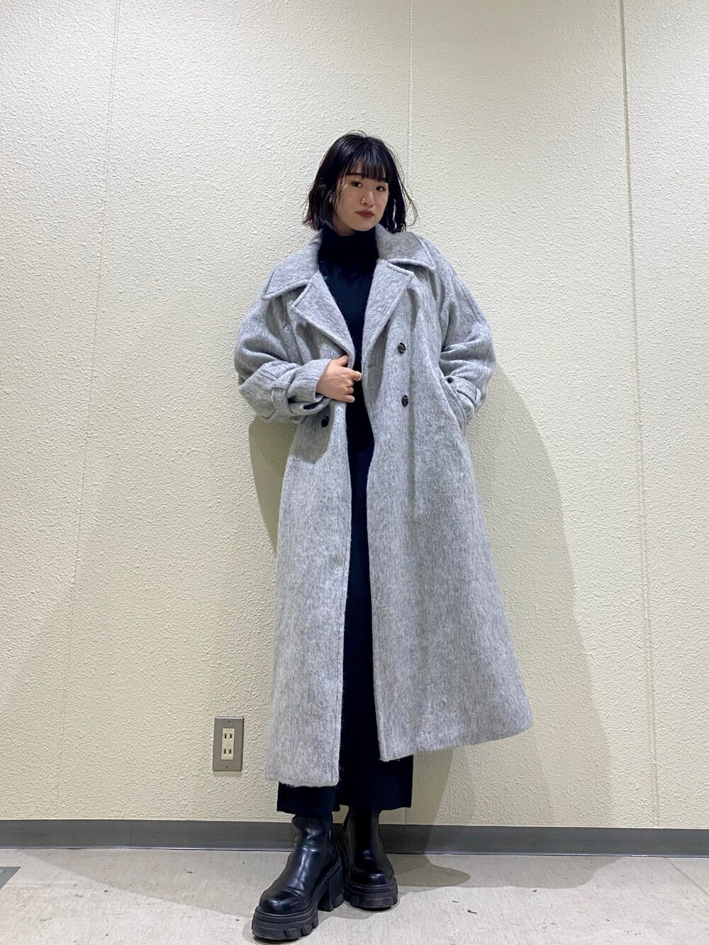 ブラック系のブーツ、グレー系のチェスターコート、ブラック系のスカートを着用したレディースの冬コーディネートの3枚目の写真