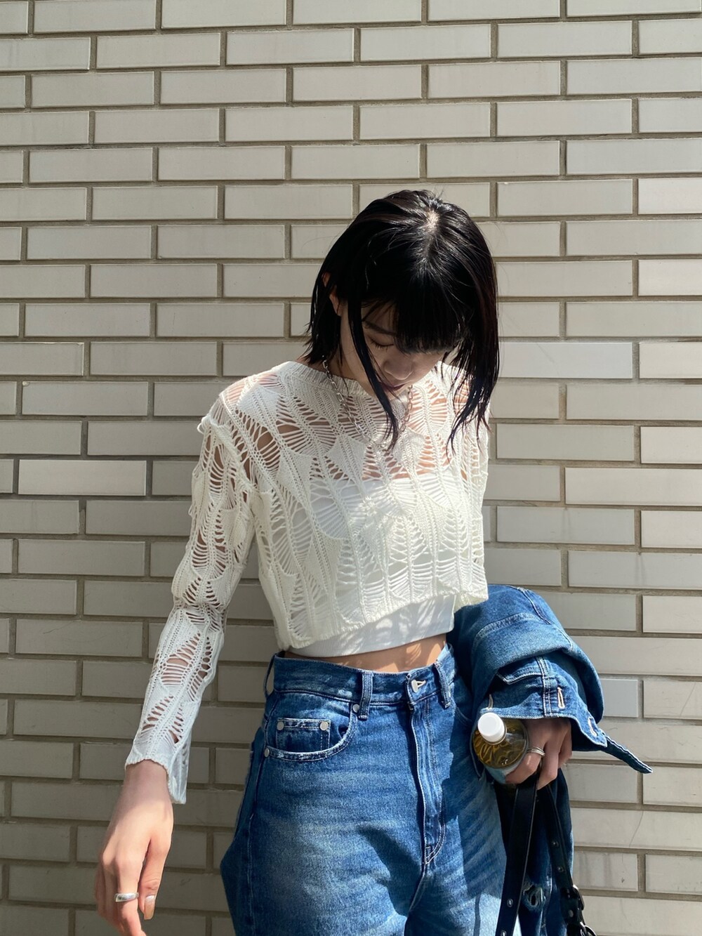 ブラック系のブーツ、ブラック系のハンドバッグ、ブルー系のデニムパンツを着用したレディースの春コーディネートの8枚目の写真