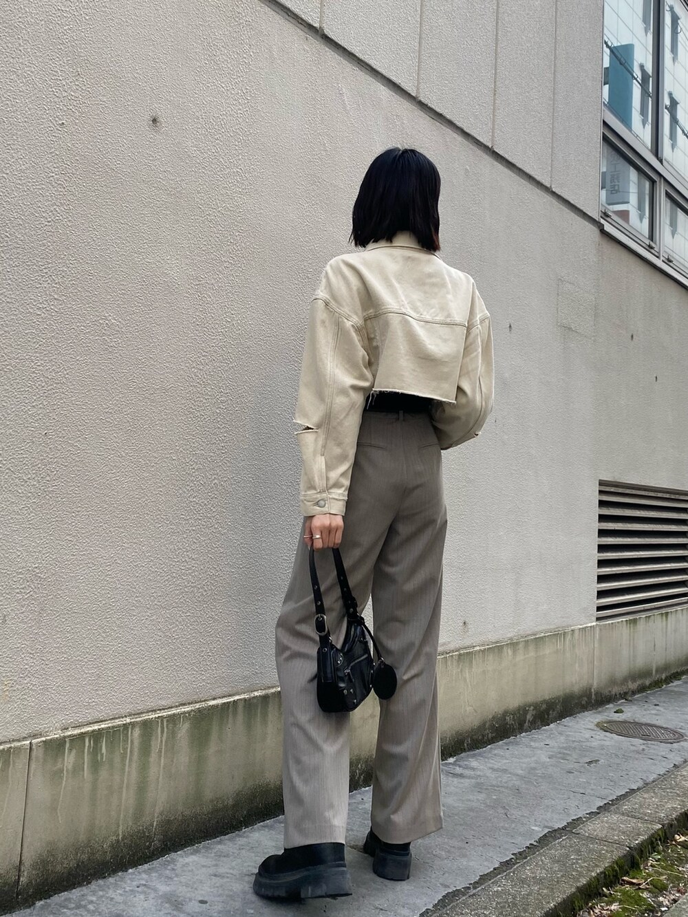 ホワイト系のデニムジャケット、ブラック系のキャミソール、ブラック系のハンドバッグを着用したレディースの春コーディネートの4枚目の写真