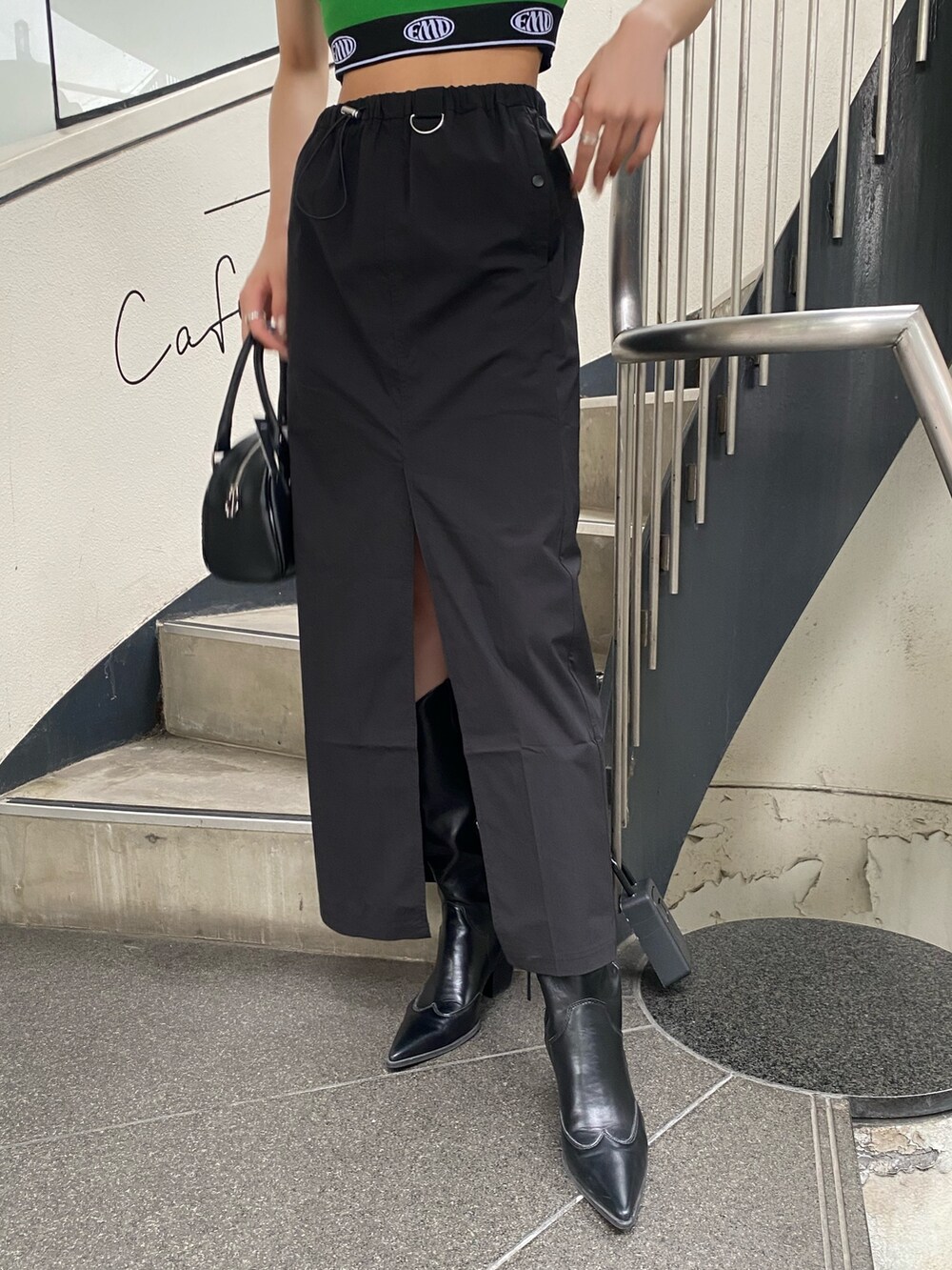 ブラック系のスカート、ブラック系のハンドバッグ、グリーン系のTシャツ/カットソーを着用したレディースの春コーディネートの8枚目の写真