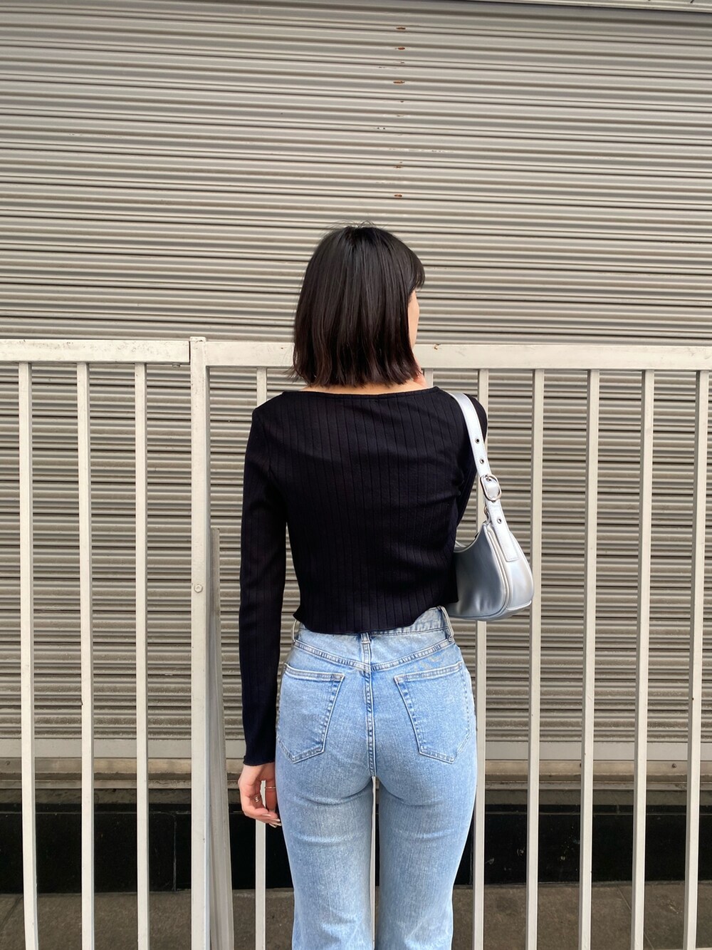 ブルー系のデニムパンツ、ブラック系のTシャツ/カットソー、シルバー系のハンドバッグを着用したレディースの春コーディネートの7枚目の写真
