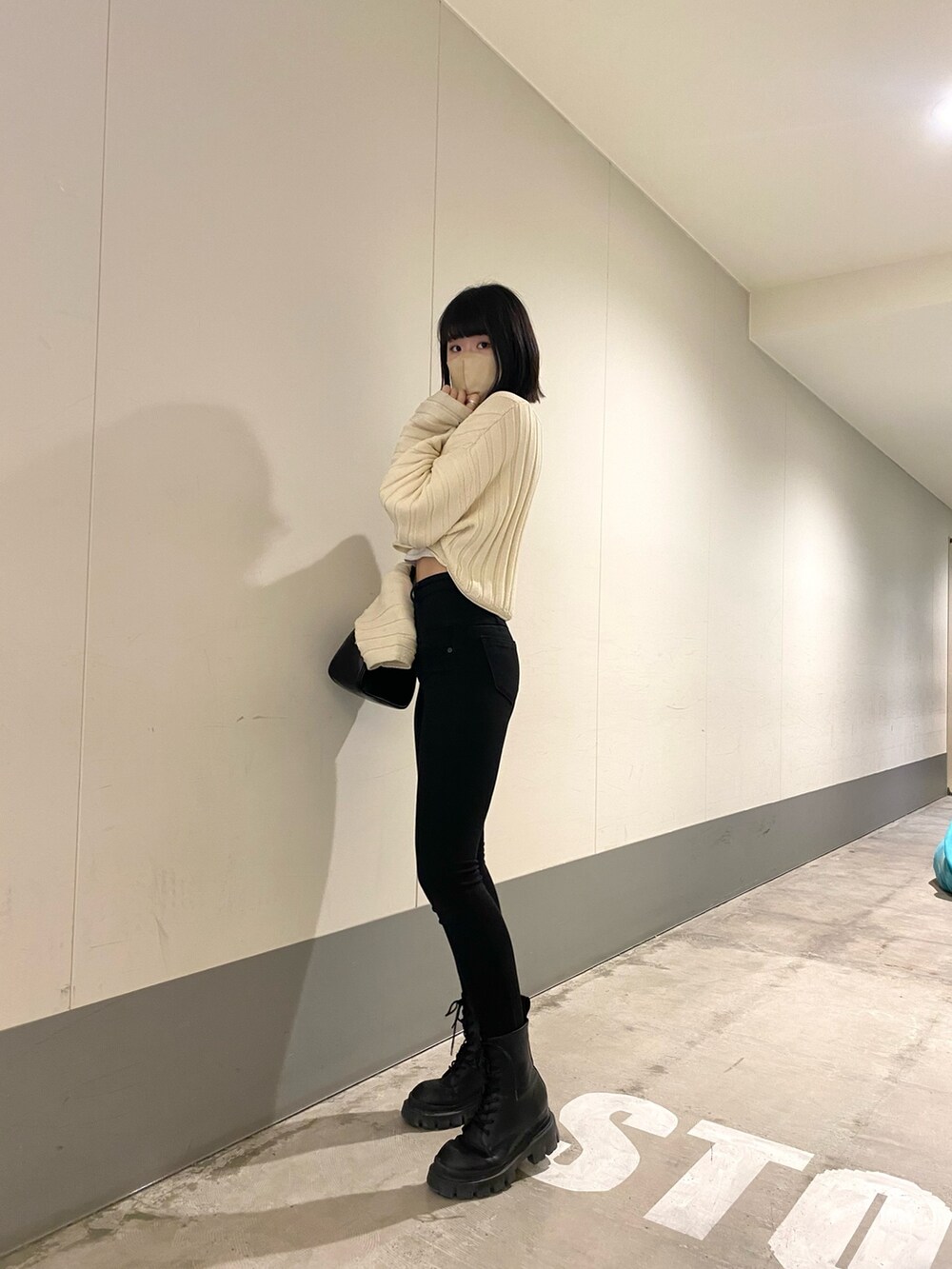 ブラック系のブーツ、ブラック系のデニムパンツ、ホワイト系のニット/セーターを着用したレディースの春コーディネートの2枚目の写真