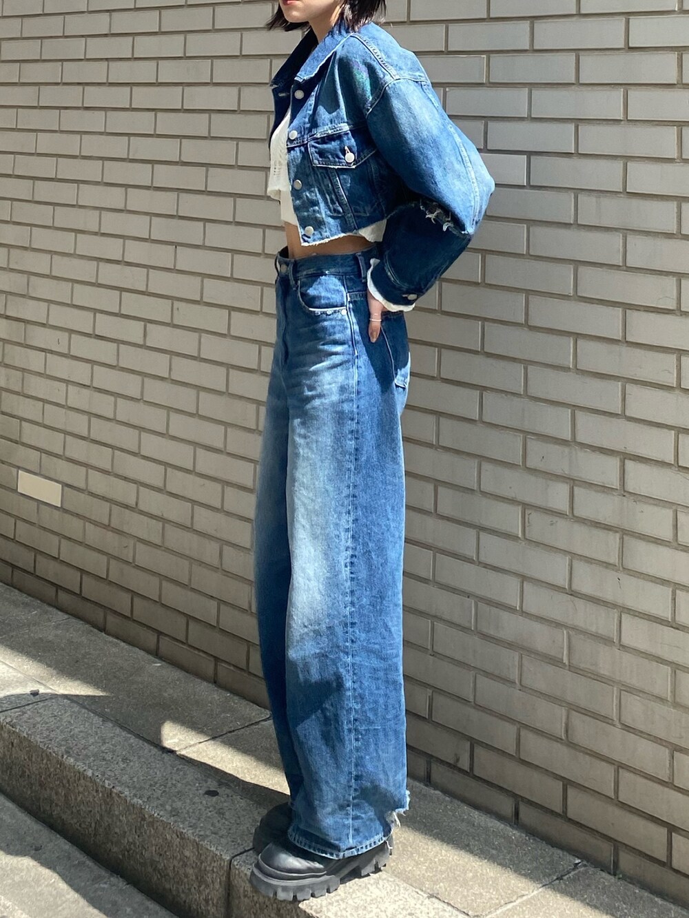 ブラック系のブーツ、ブラック系のハンドバッグ、ブルー系のデニムパンツを着用したレディースの春コーディネートの4枚目の写真