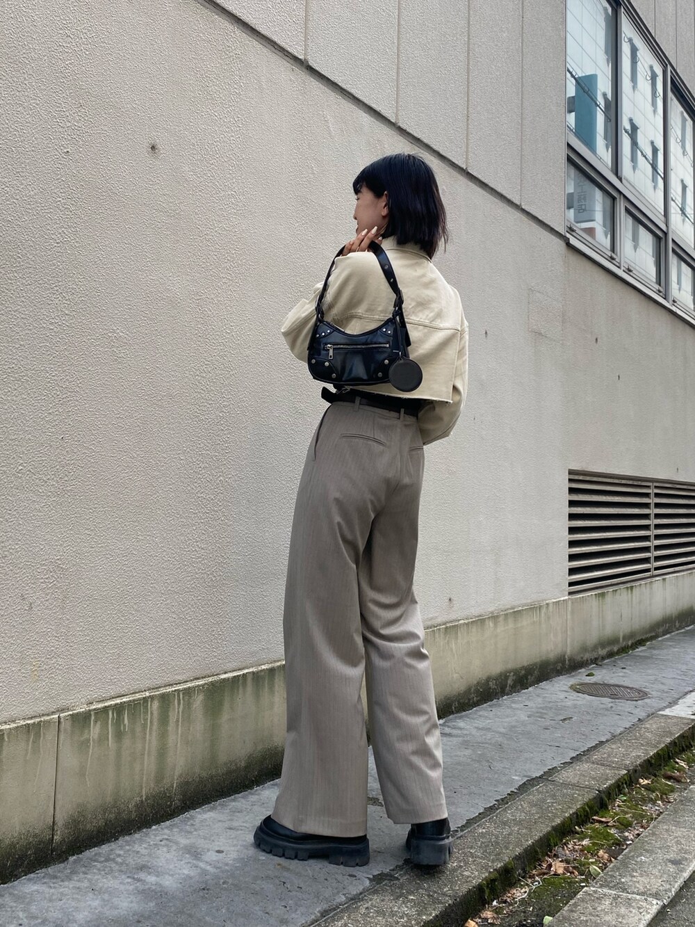 ホワイト系のデニムジャケット、ブラック系のキャミソール、ブラック系のハンドバッグを着用したレディースの春コーディネートの3枚目の写真