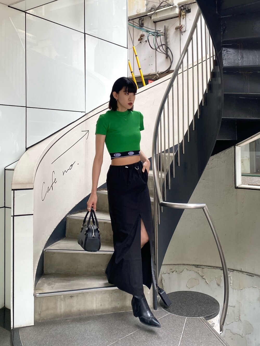ブラック系のスカート、ブラック系のハンドバッグ、グリーン系のTシャツ/カットソーを着用したレディースの春コーディネートの5枚目の写真