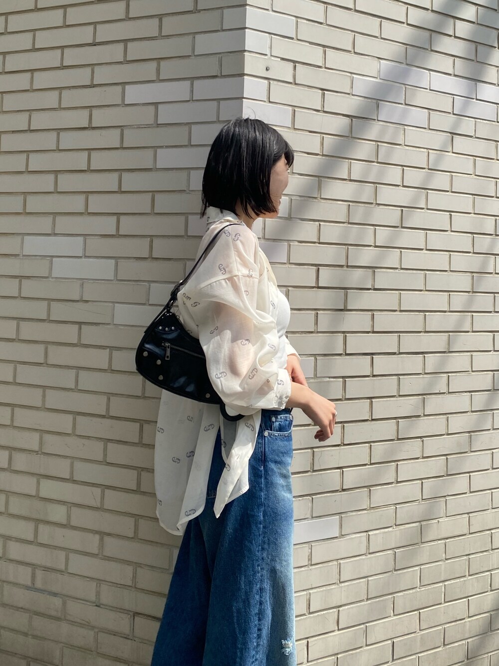 ブラック系のサンダル、ブラック系のハンドバッグ、ブルー系のデニムパンツを着用したレディースの春コーディネートの6枚目の写真